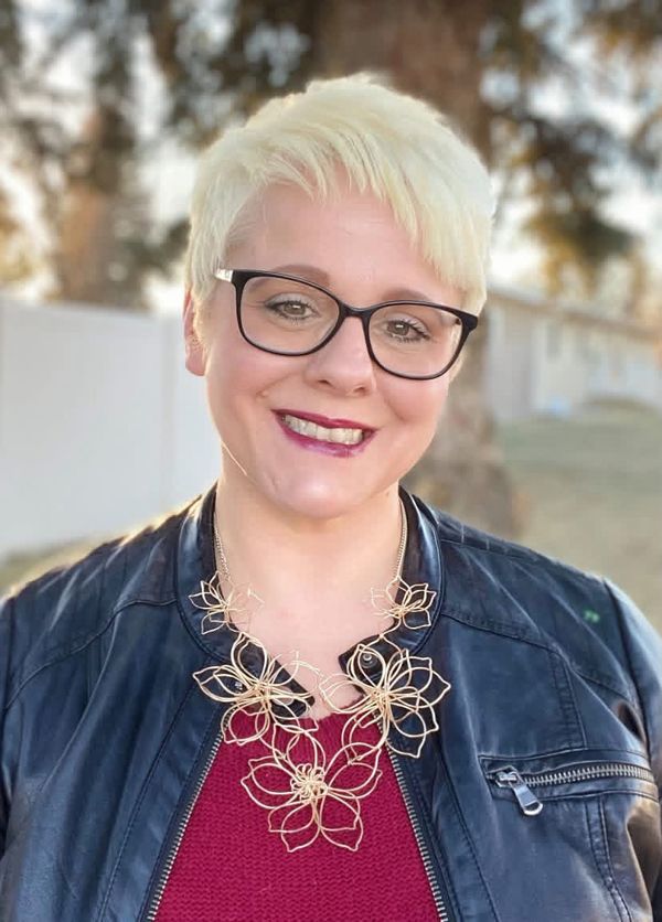 Elisheba Haxby, developmental editor, smiling outdoors in glasses and a leather jacket